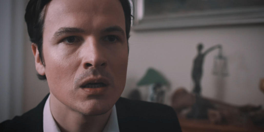 In a movie production, actor Frederic Stromenger can be seen in a close-up against a blurred background, looking anxiously past the camera on the right.