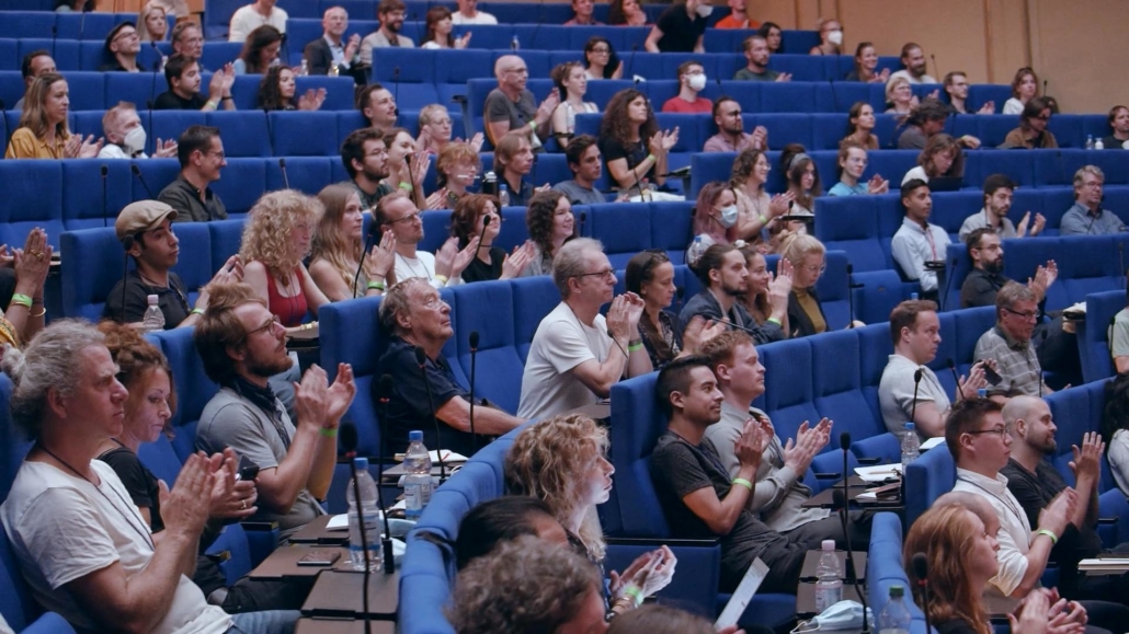 As livestream company Berlin we were in the auditorium of the Langebeck-Virchow-Haus, and photographed the round blue-cushioned rows of seats with applauding people from the side.