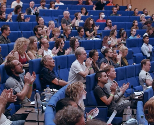 As livestream company Berlin we were in the auditorium of the Langebeck-Virchow-Haus, and photographed the round blue-cushioned rows of seats with applauding people from the side.
