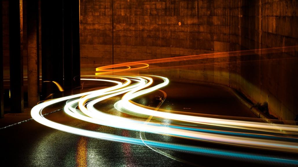 In the picture we see light traces in orange and turquoise tones on a street at night as part of a long exposure, which can be used for image films.