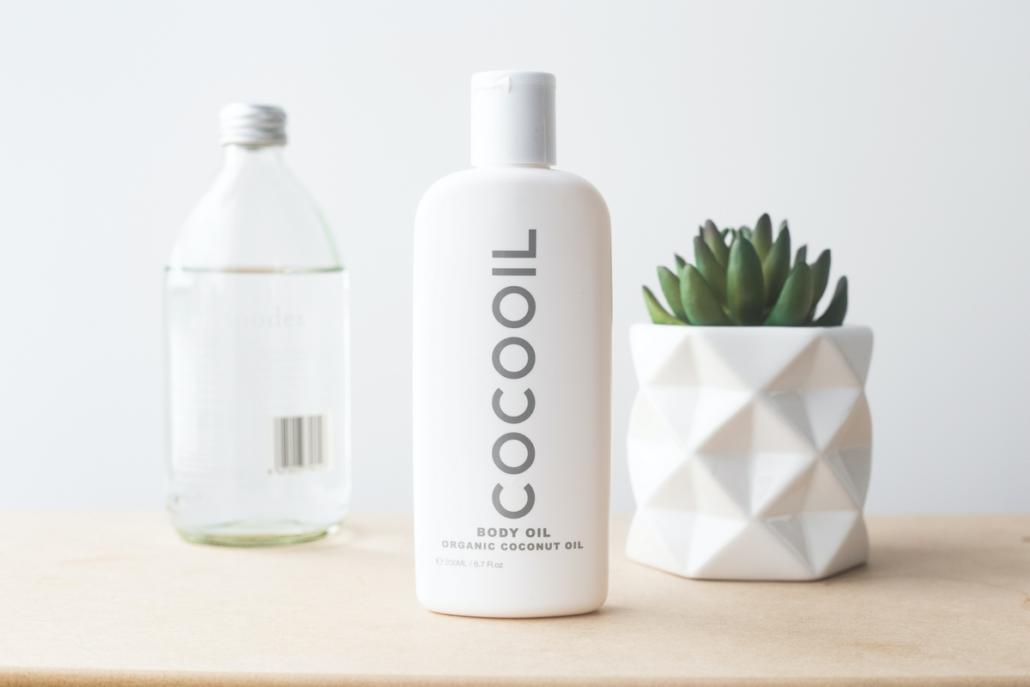 From the front we see a white bottle of body oil on a wooden background. Further back on the left is a glass bottle with a transparent liquid, further back on the right is a cactus-like plant with short, thick leaves in a white, stylishly designed pot. If you want to have a TV spot created, this kind of presentation is very suitable, because it convincingly shows off your product, as shown here, and the scene is very bright and at the same time softly illuminated.