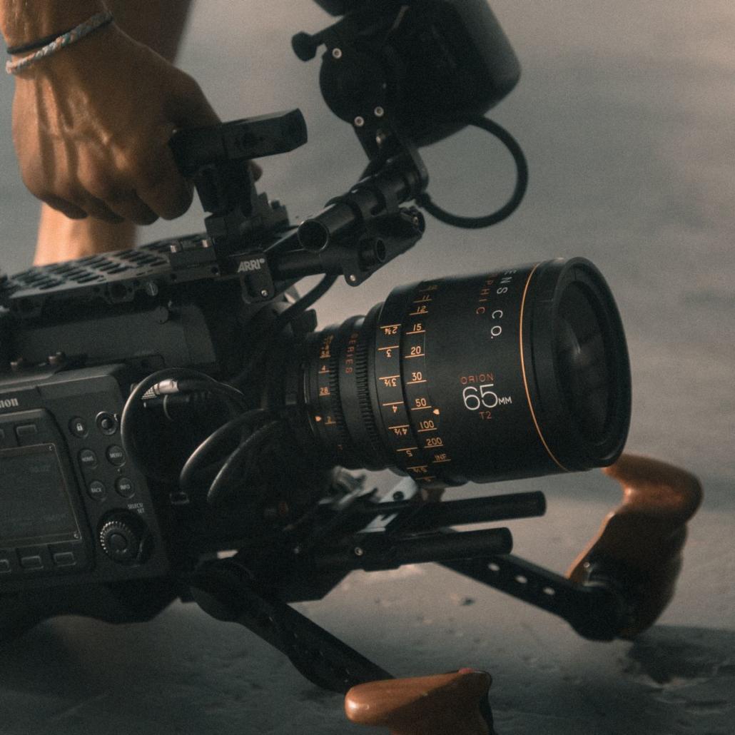 This picture shows a rigged professional camera placed on the floor. We see the hand of the cameraman of a video agency, as he is about to pull up the camera with a handle.